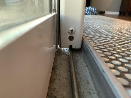Sliding glass door showing severe misalignment with large uneven gap at bottom and tight gap at top requiring professional adjustment service