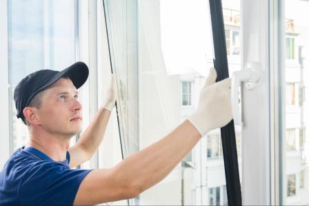 Technician installing new tempered glass panel into sliding door frame with proper shimming and weatherproof sealing